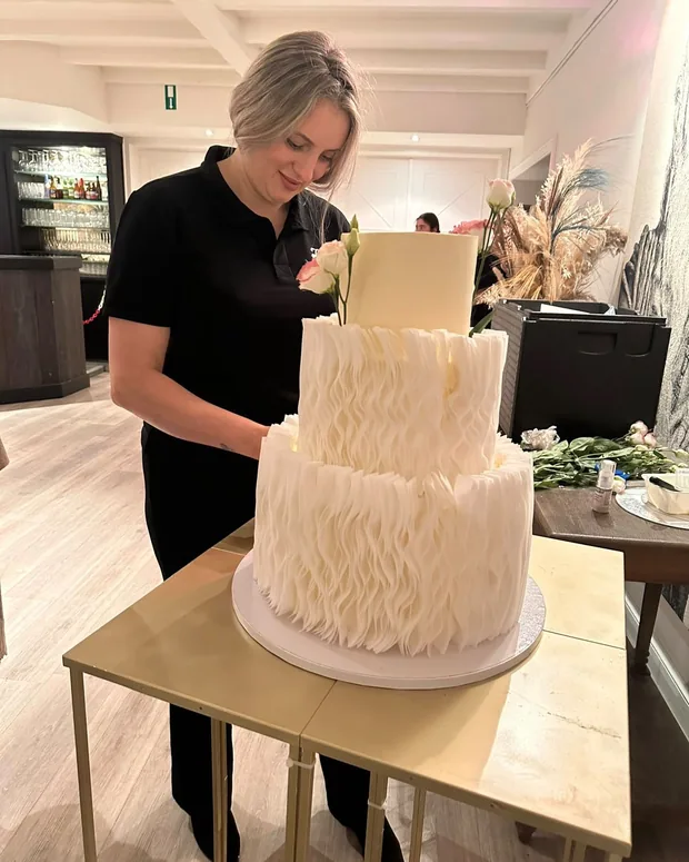 Anka setting the top tier on the ruffle cake