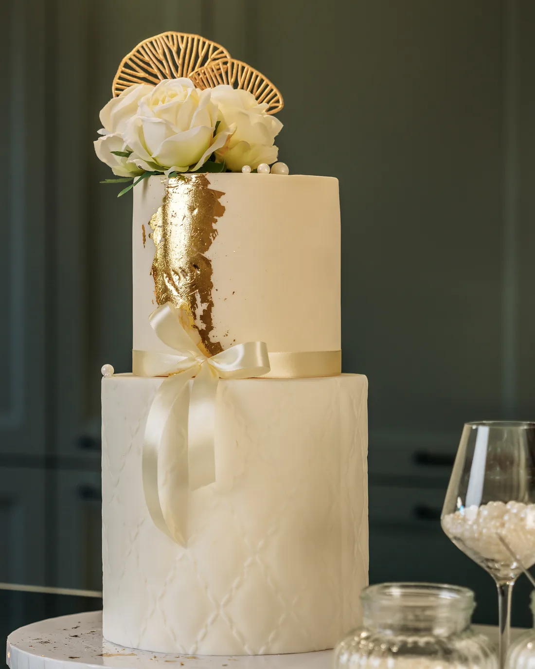 Ivory wedding cake with gold leaf and a satin bow