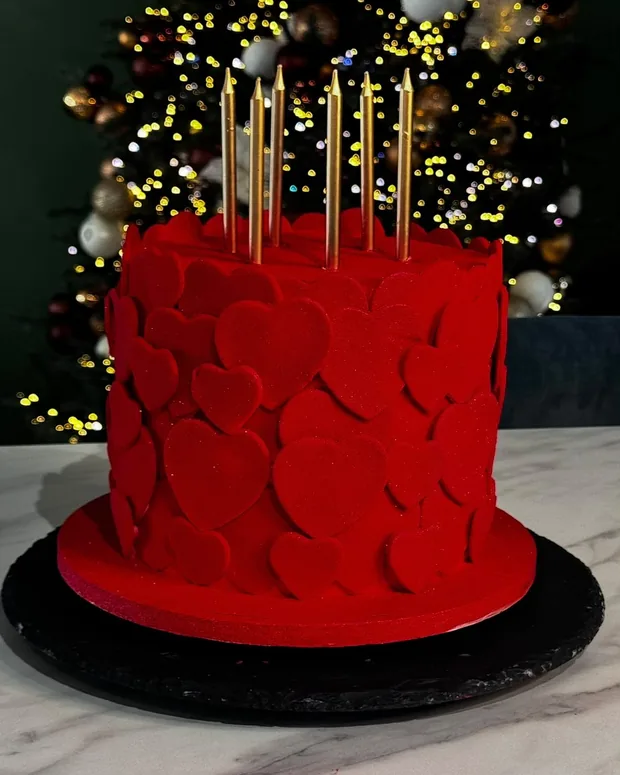 Red cake with petals and golden candles